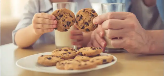 Photo of two people tapping two cookies together